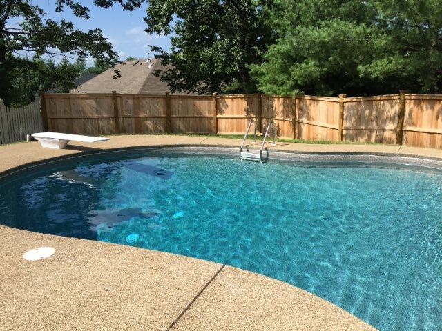 A large swimming pool with a wooden fence surrounding it