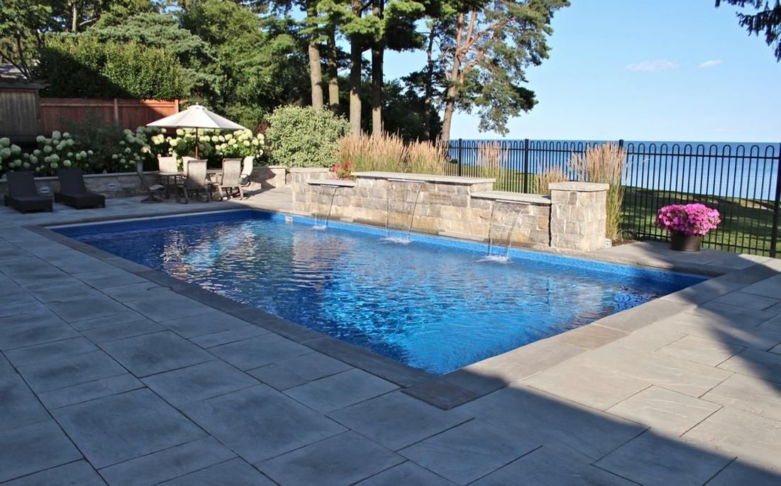 There is a large swimming pool in the backyard with a view of the ocean.