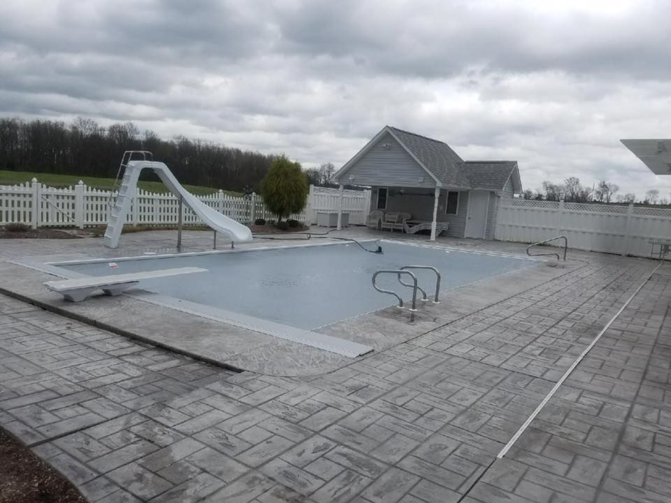 A large swimming pool with a slide and a house in the background