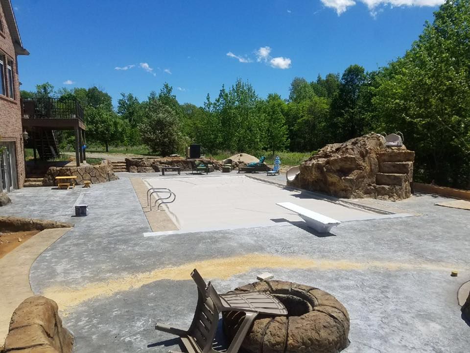 A patio with a fire pit and a bench in front of a house
