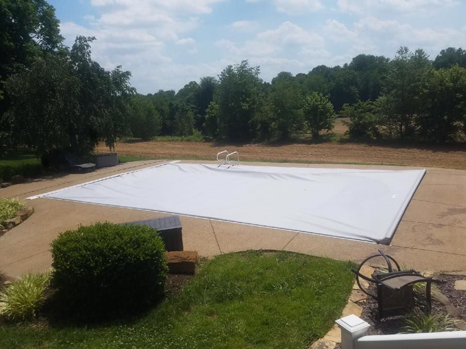 A large white tarp is covering a swimming pool in a backyard.