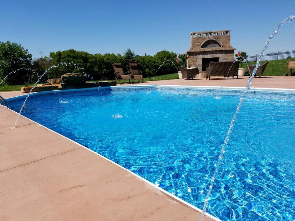 A large swimming pool with a fireplace in the background