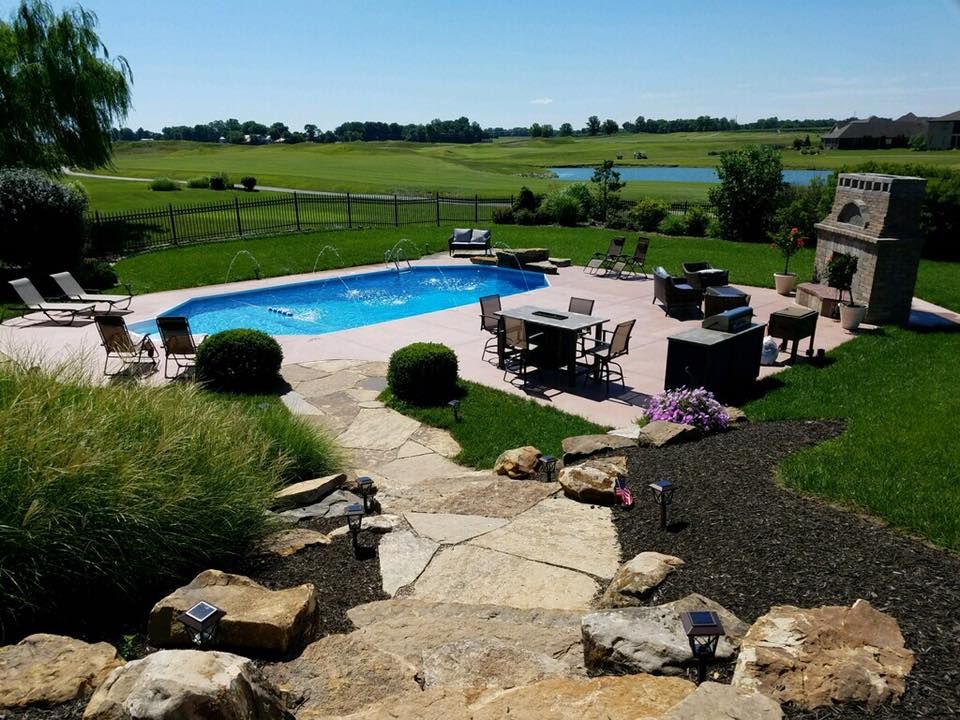 A large swimming pool is in the middle of a lush green yard