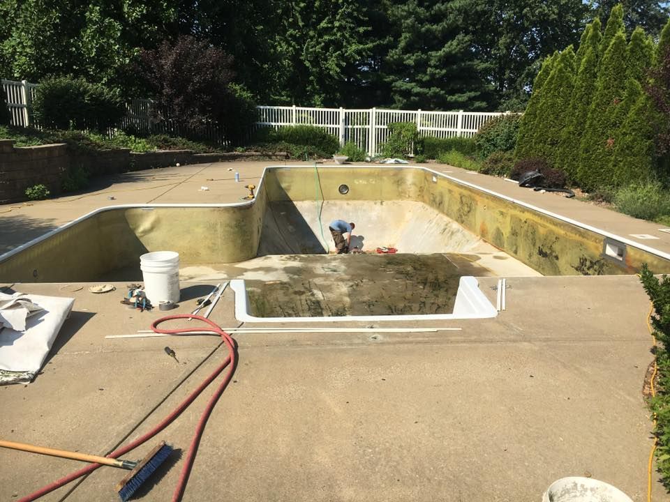 A man is working on a swimming pool in a backyard