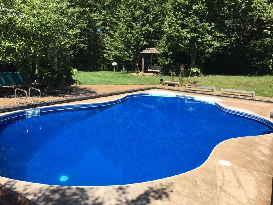 A large blue swimming pool with a gazebo in the background