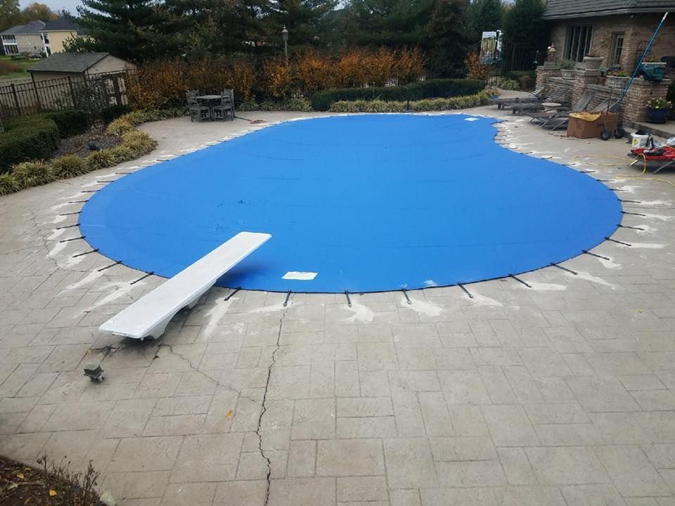 A swimming pool with a blue cover and a diving board