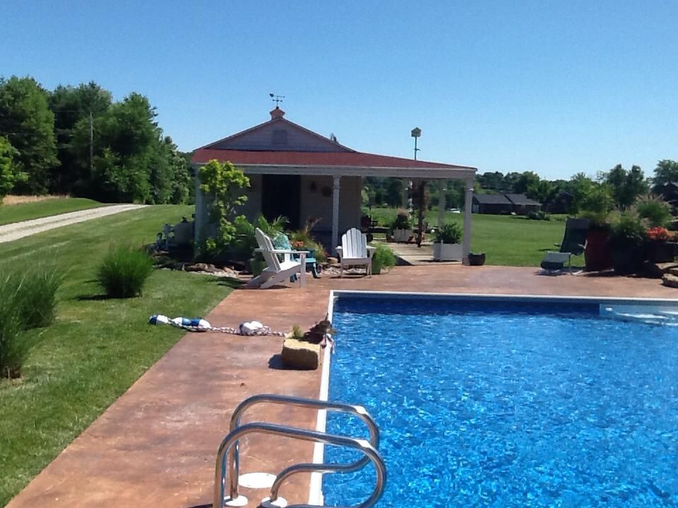 A large swimming pool with a house in the background