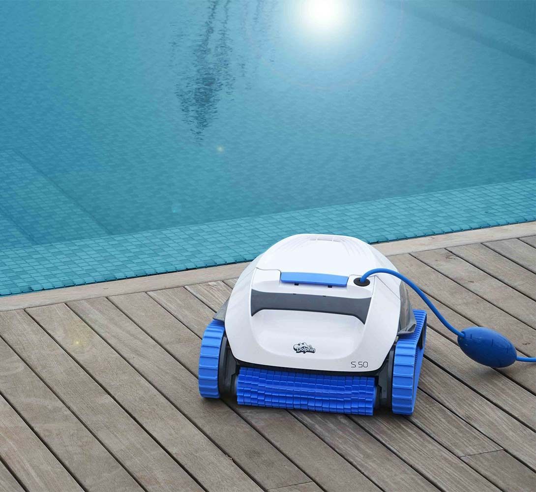 A robotic pool cleaner is sitting on a wooden deck next to a swimming pool.