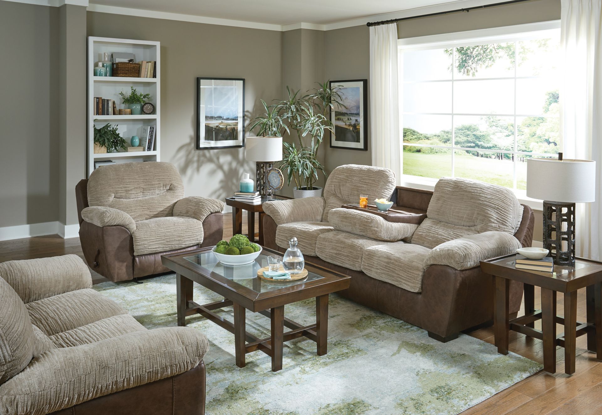 Cozy beige living room with sofas, coffee table, bookshelf, and a large window letting in daylight