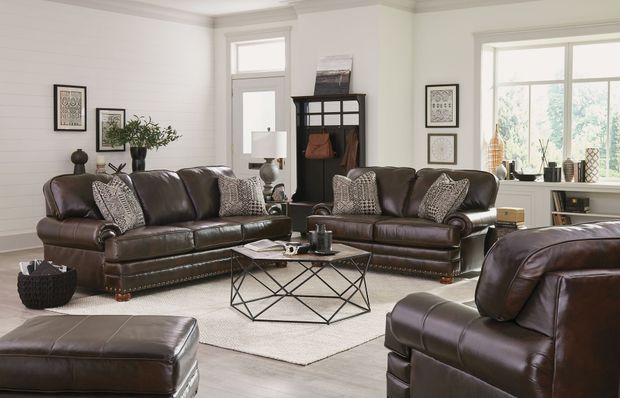 Modern living room with dark brown leather sofas, patterned pillows, and a geometric coffee table