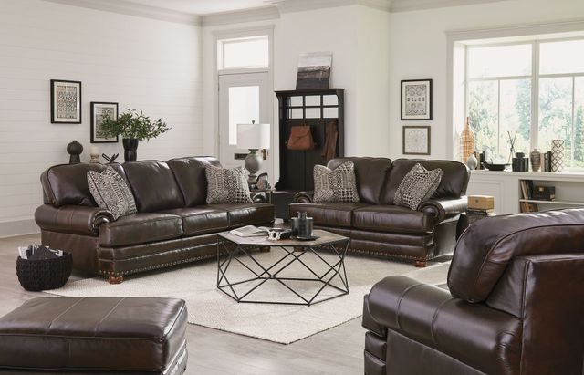 Modern living room with dark brown leather sofas, patterned pillows, and a geometric coffee table