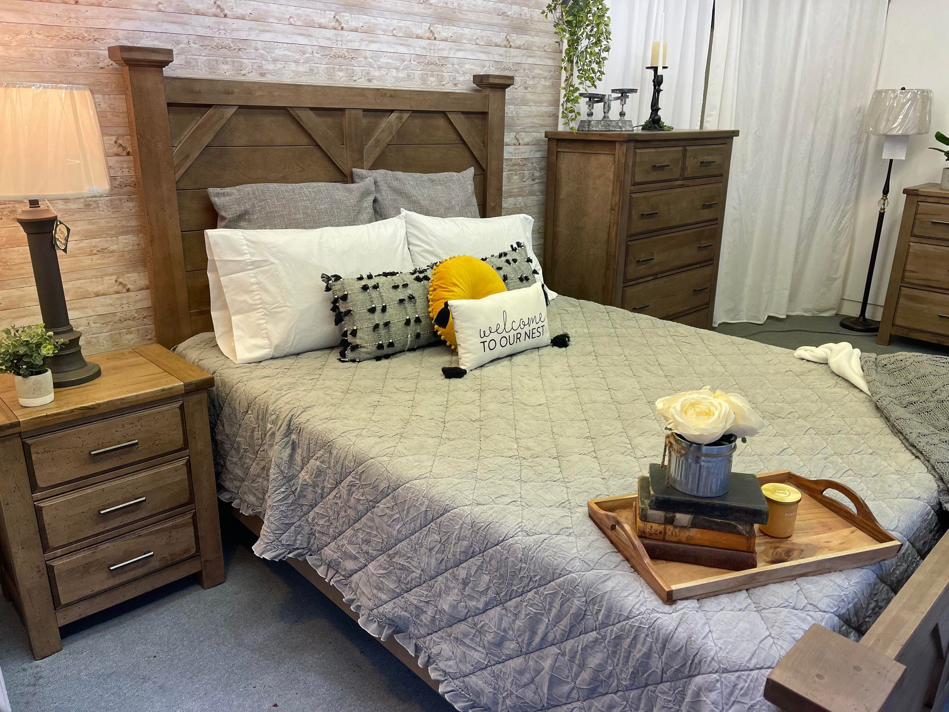 Cozy bedroom with a gray upholstered bed, wooden nightstands, and a tray on the blanket