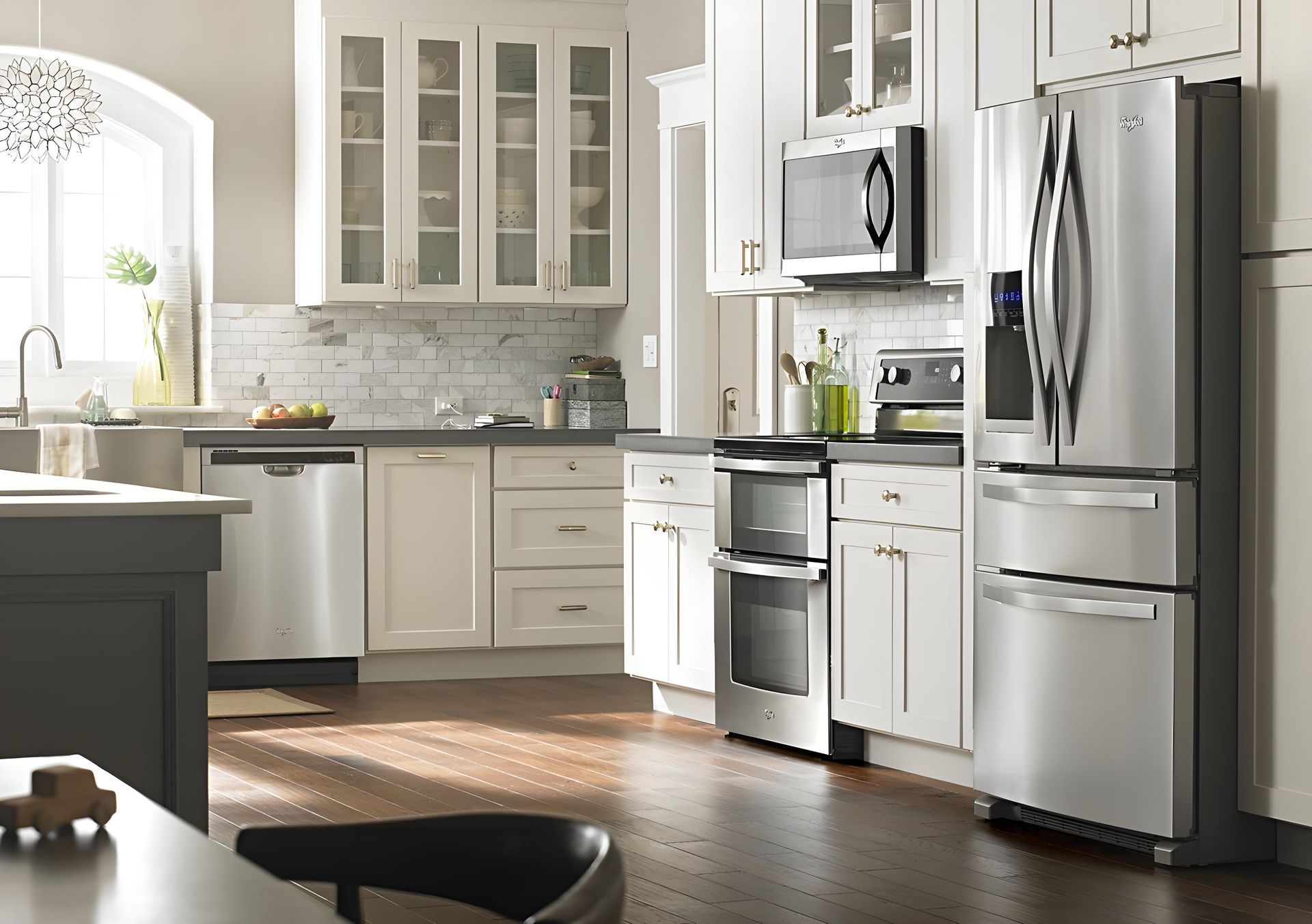 Bright modern kitchen with white cabinets, stainless steel appliances, and sunlight on hardwood floors