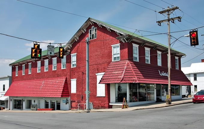 Red two-story corner building with white-trimmed windows at a street intersection, under traffic lights.