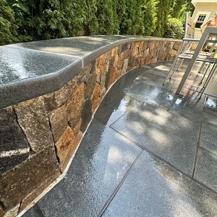 A stone wall with a granite counter top on a patio.