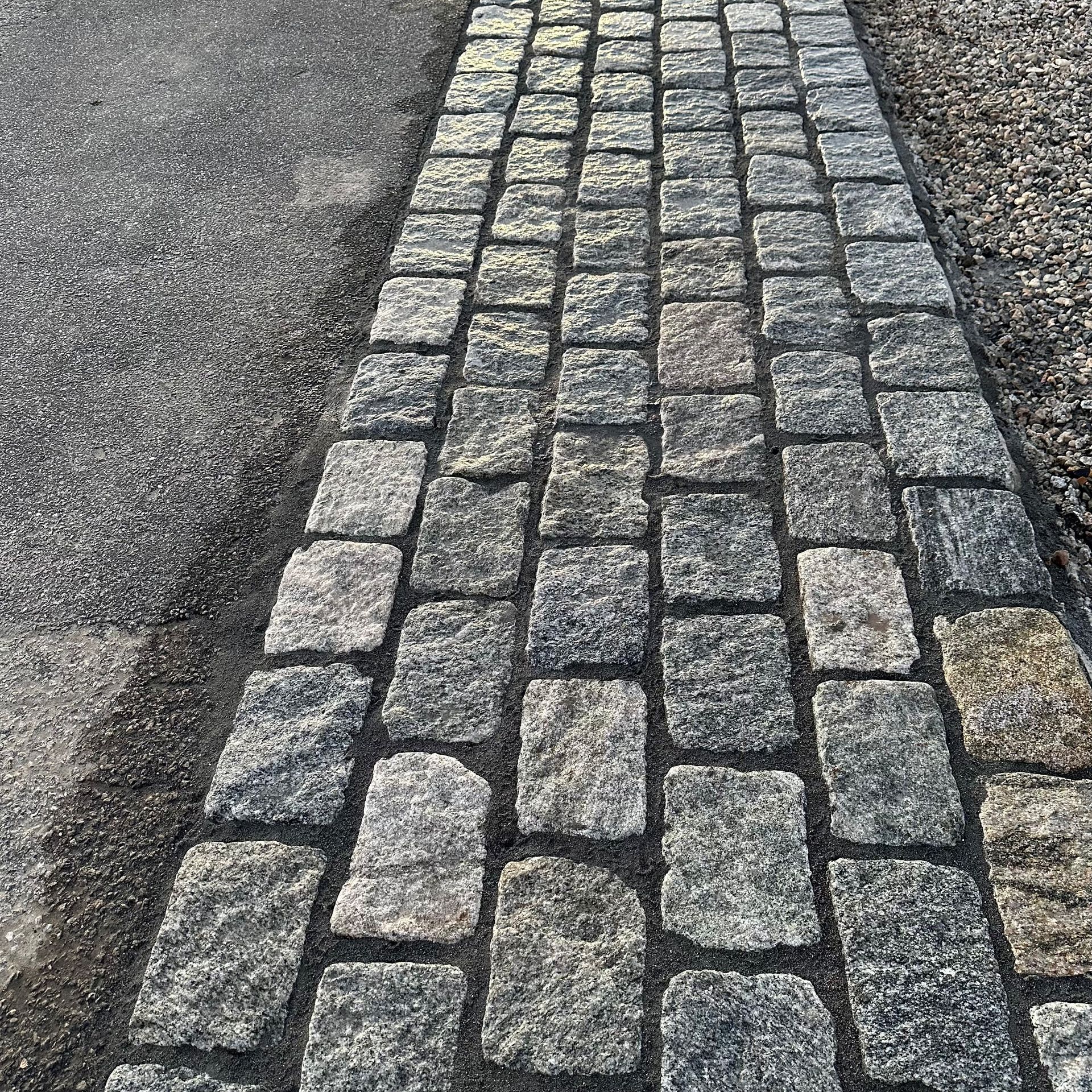 A cobblestone walkway along the side of a road.