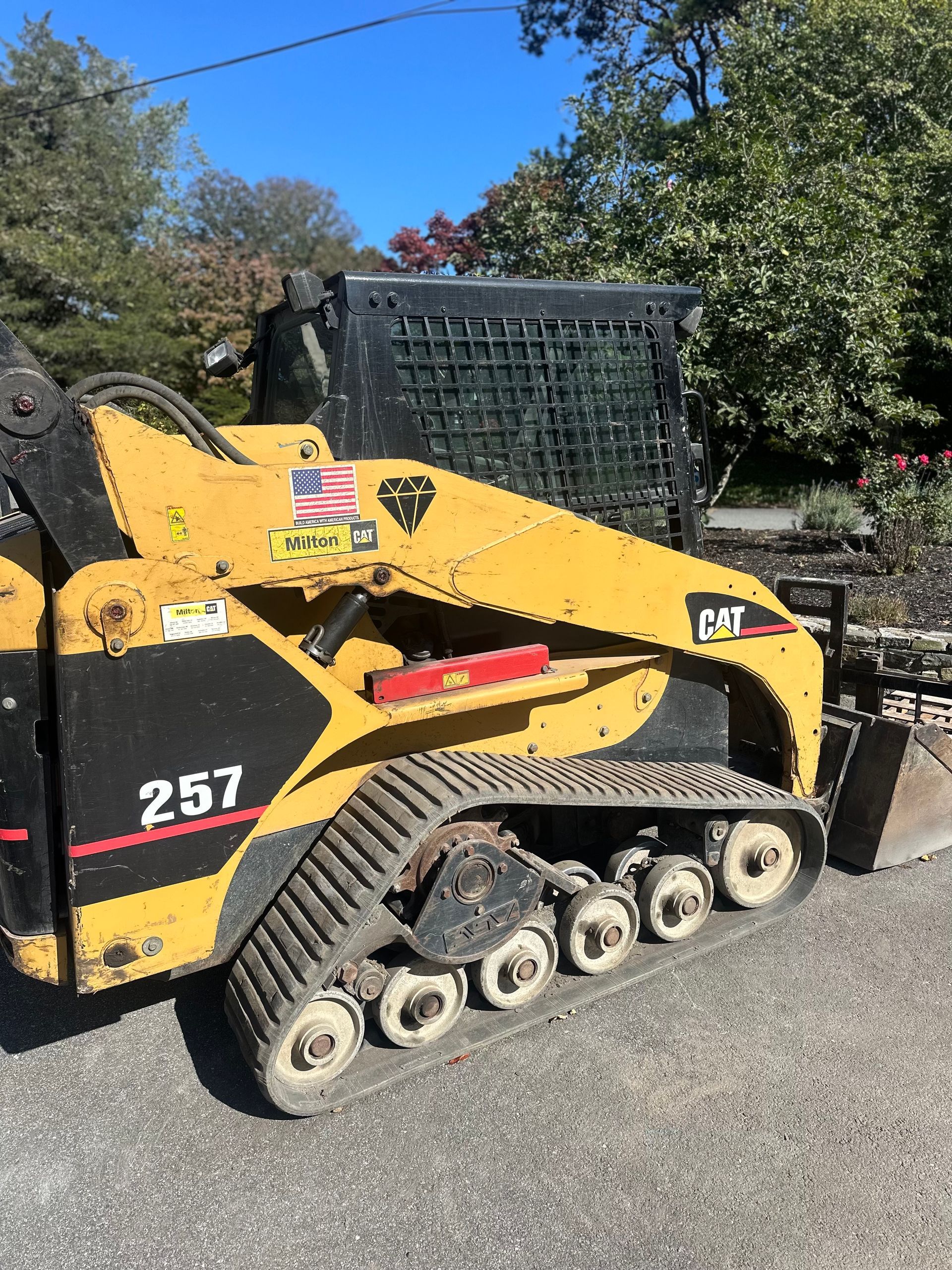 A yellow and black cat 257 track loader is parked on the side of the road.