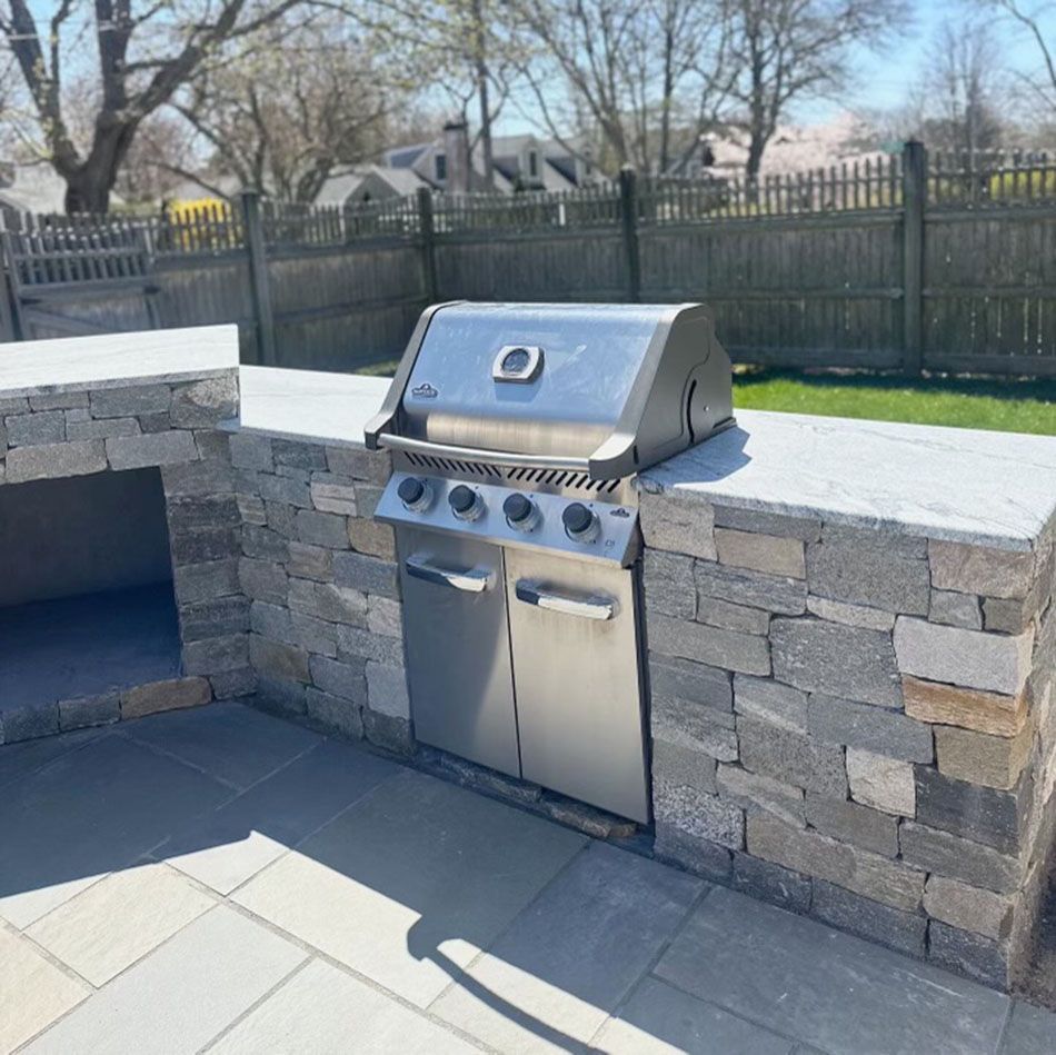 A stainless steel grill is built into a stone wall