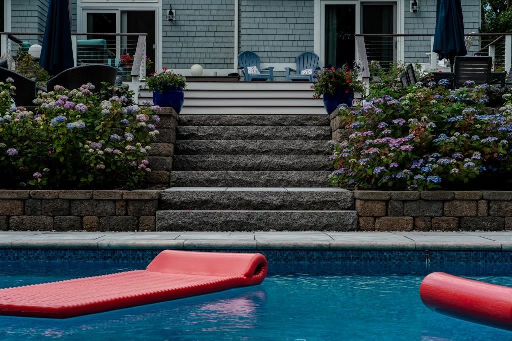 Two red rafts are floating in a swimming pool in front of a house