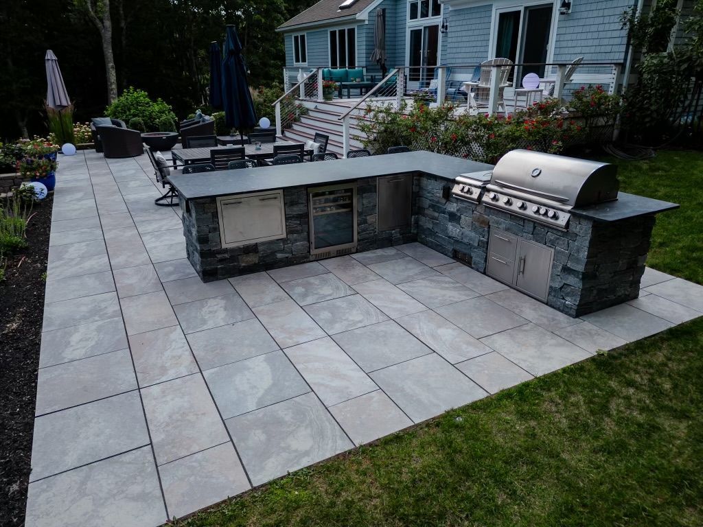 A large outdoor kitchen with a grill in the backyard of a house