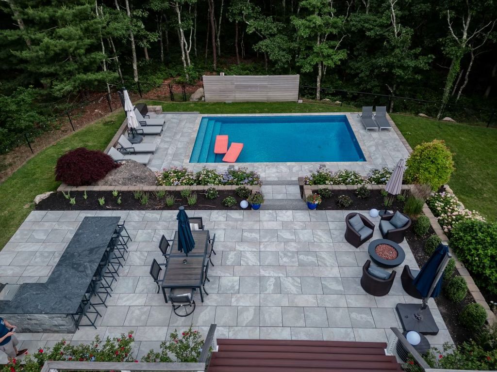 An aerial view of a backyard with a large swimming pool and patio furniture