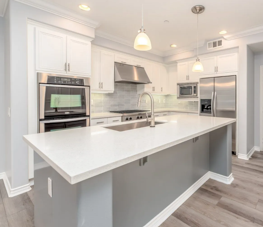 Bright modern kitchen with white cabinets, stainless appliances, and a large island with sink