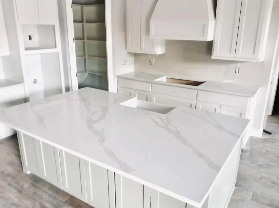 Bright white modern kitchen with marble island, white cabinetry, and built-in stainless refrigerator