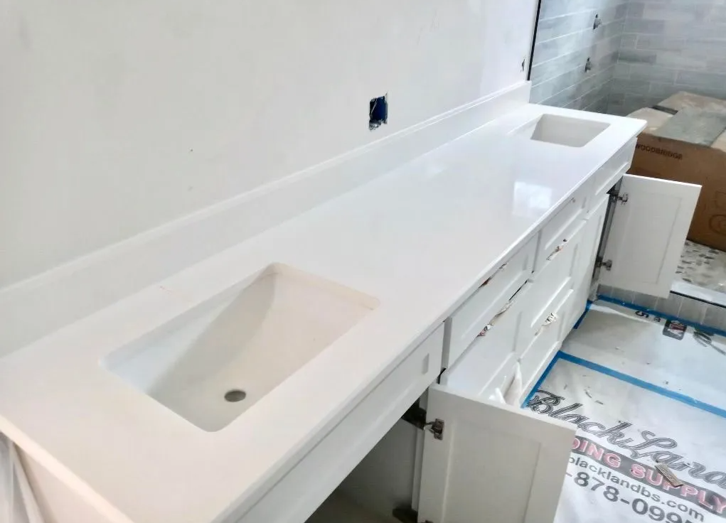 White double bathroom vanity with two sinks and cabinets under installation in a tiled room