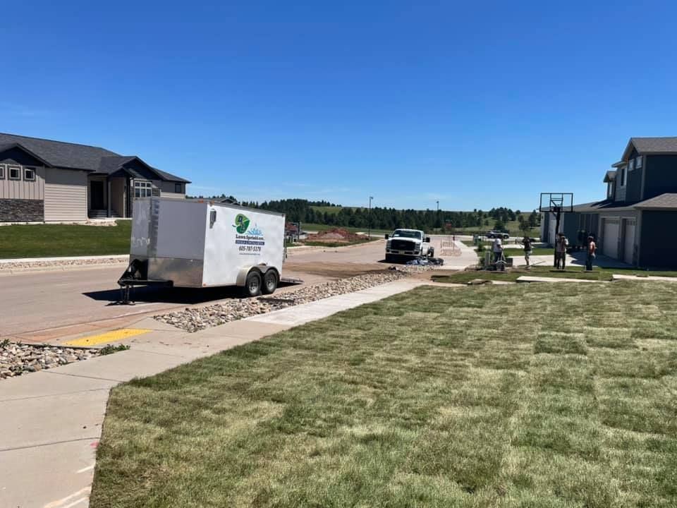 a trailer is parked on the side of the road next to a lush green lawn