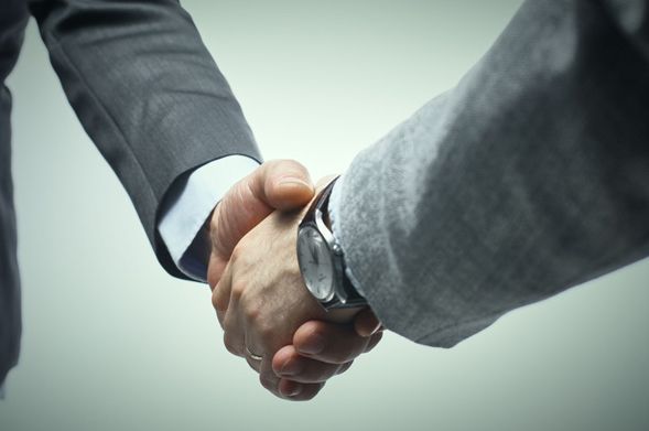 A man wearing a watch is shaking hands with another man.