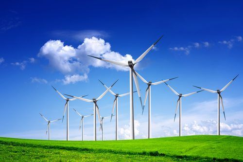 A row of wind turbines are sitting on top of a grassy hill.