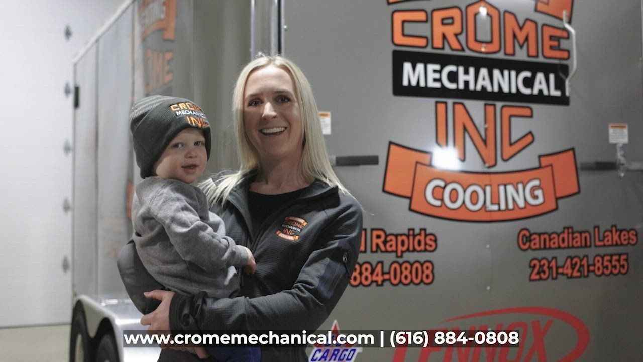 Woman holding a child smiles in front of a truck with