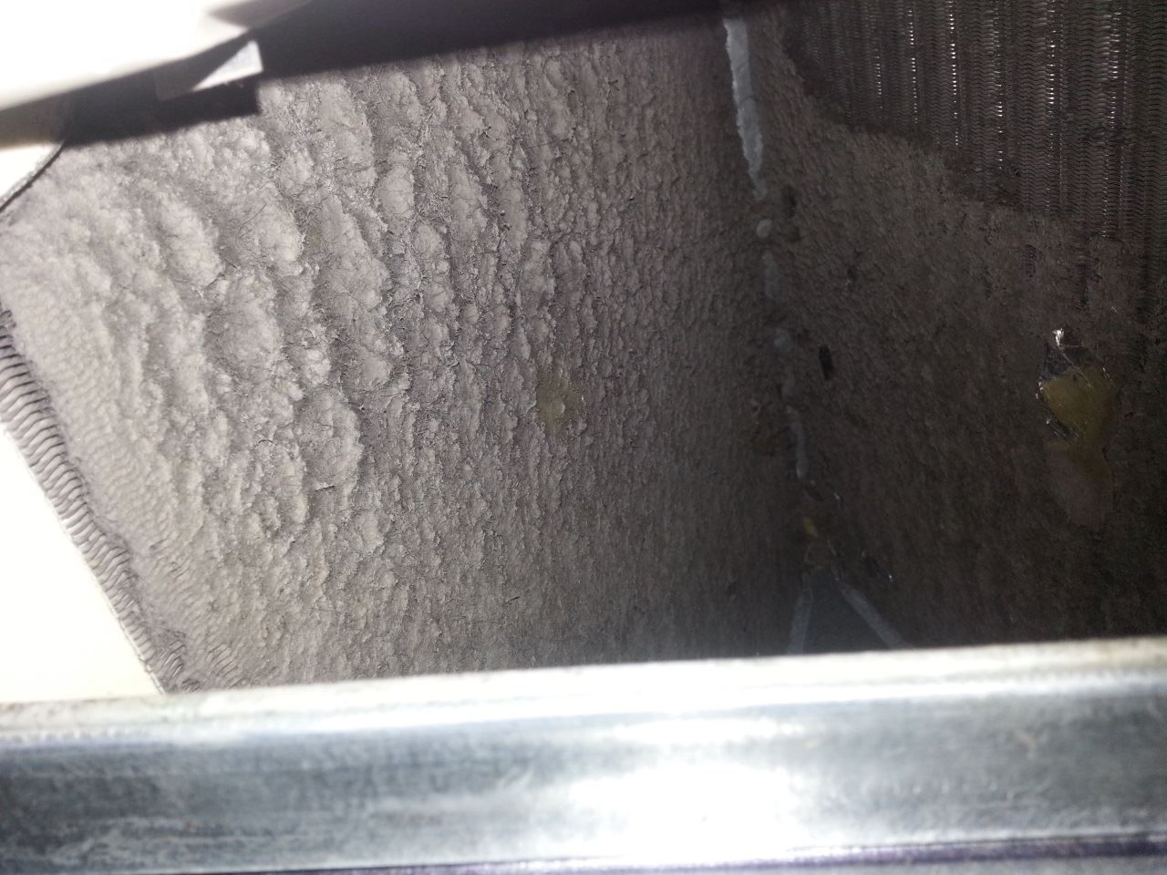 A close up of a dirty air vent with a metal frame.