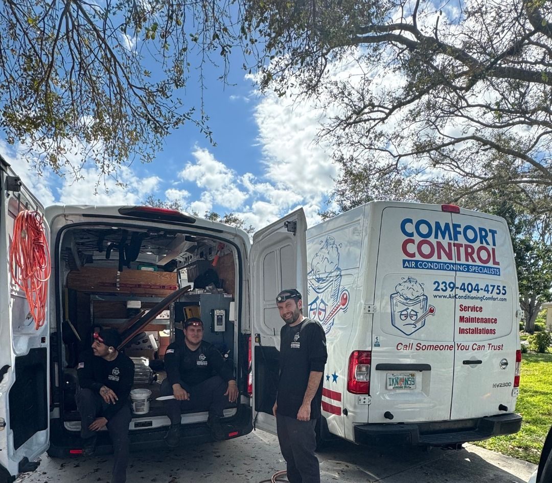 Two comfort control vans are parked next to each other in a driveway.