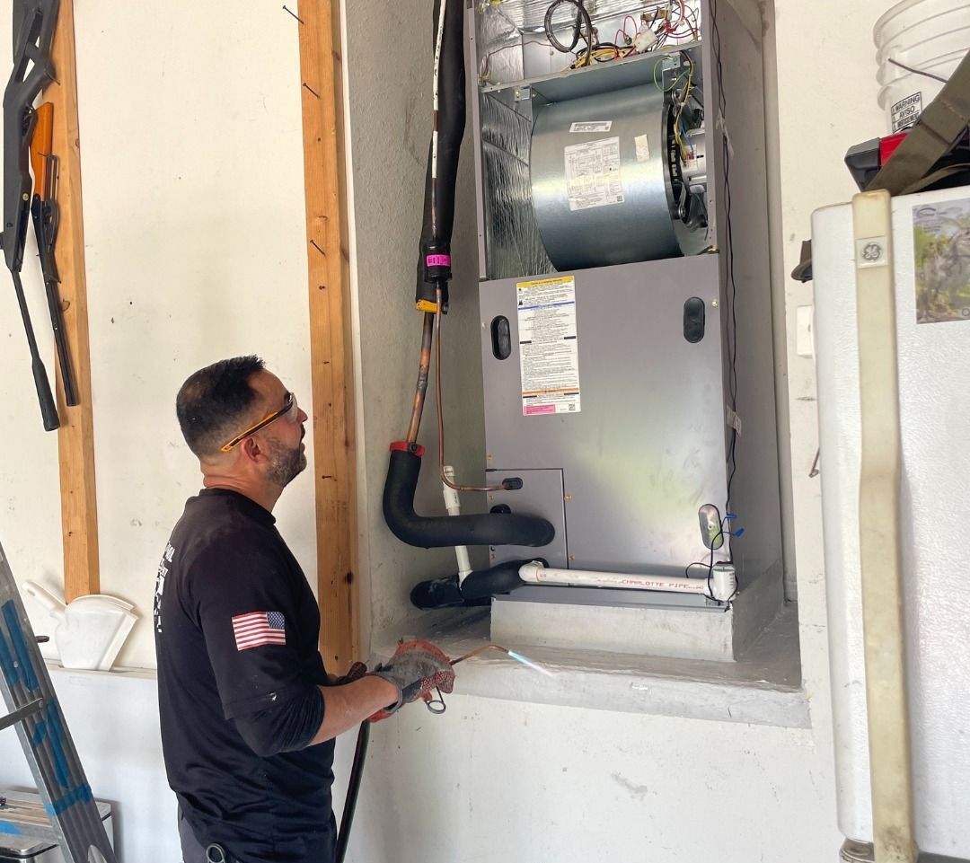 A man is working on an air conditioner in a garage.