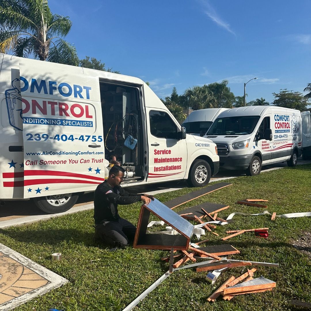 A man is kneeling in front of a comfort control van.