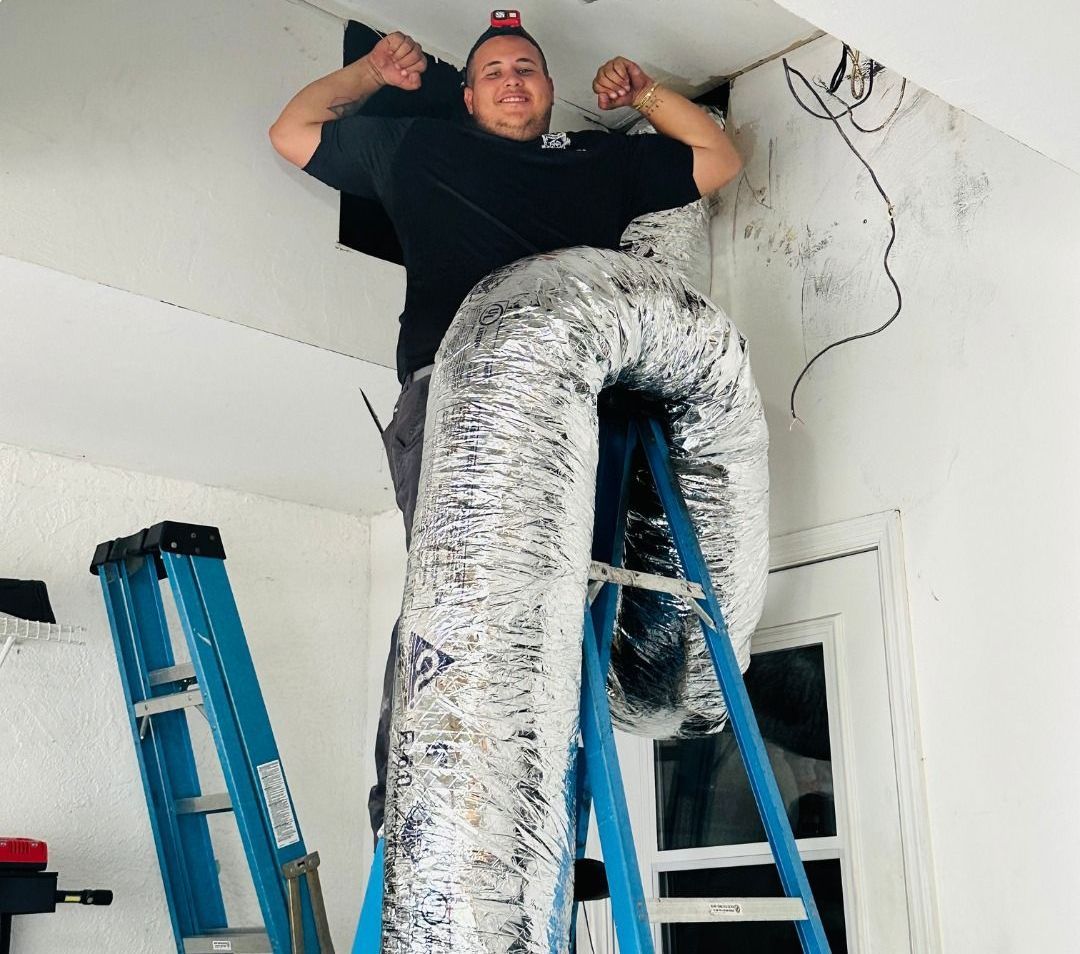A man is standing on a ladder next to a duct that says comfort control