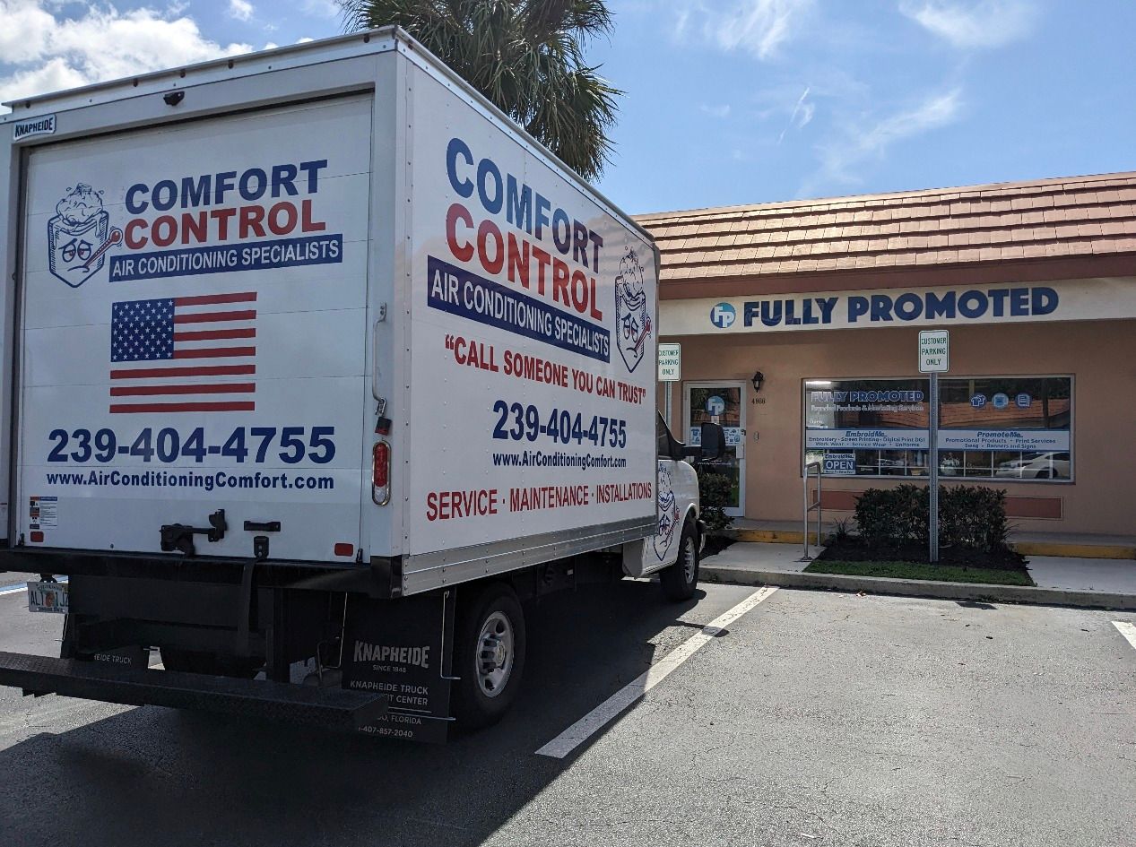 A white comfort control truck is parked in front of a building