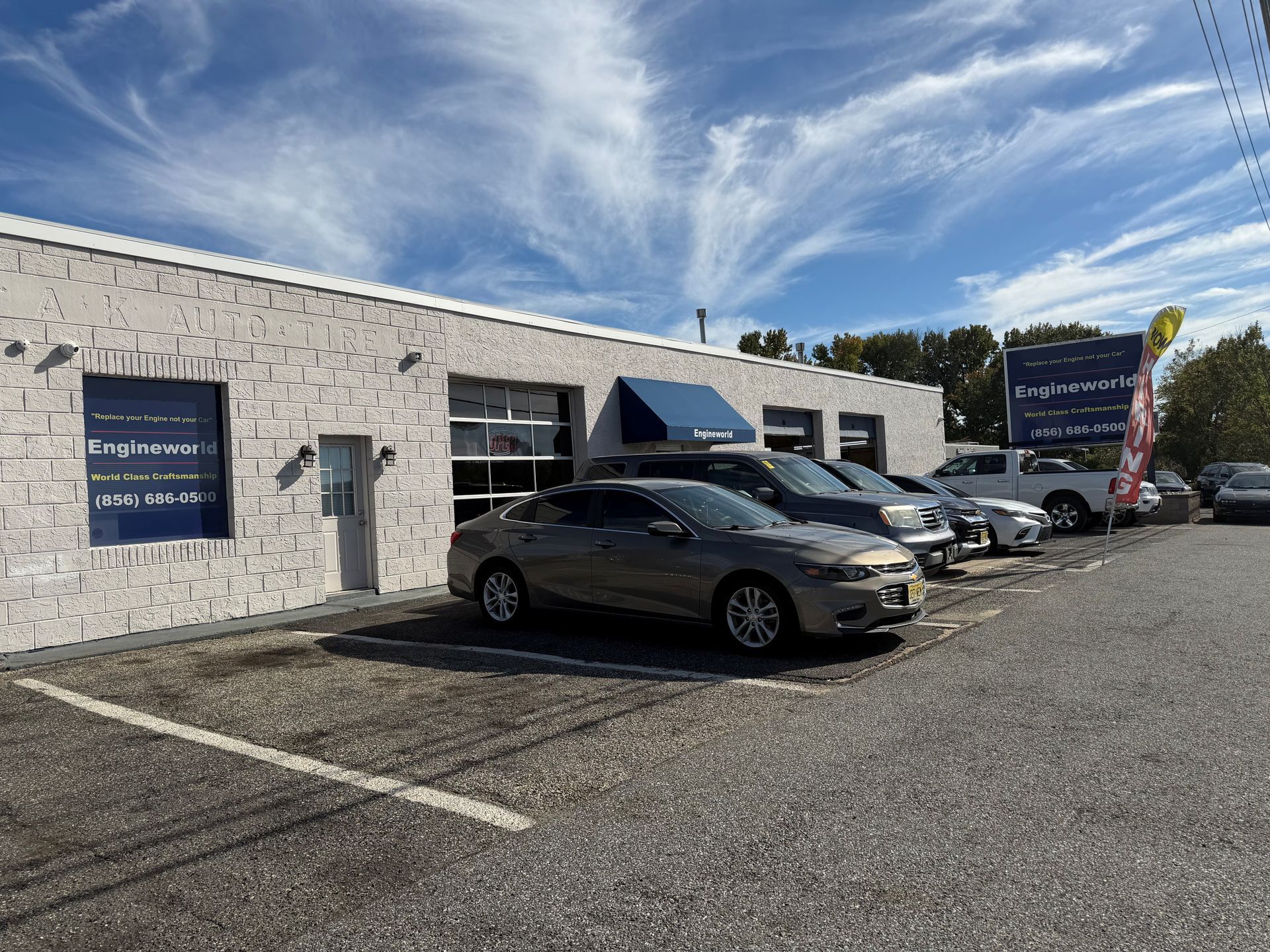 Small roadside business with parked cars under a blue sky and power lines.