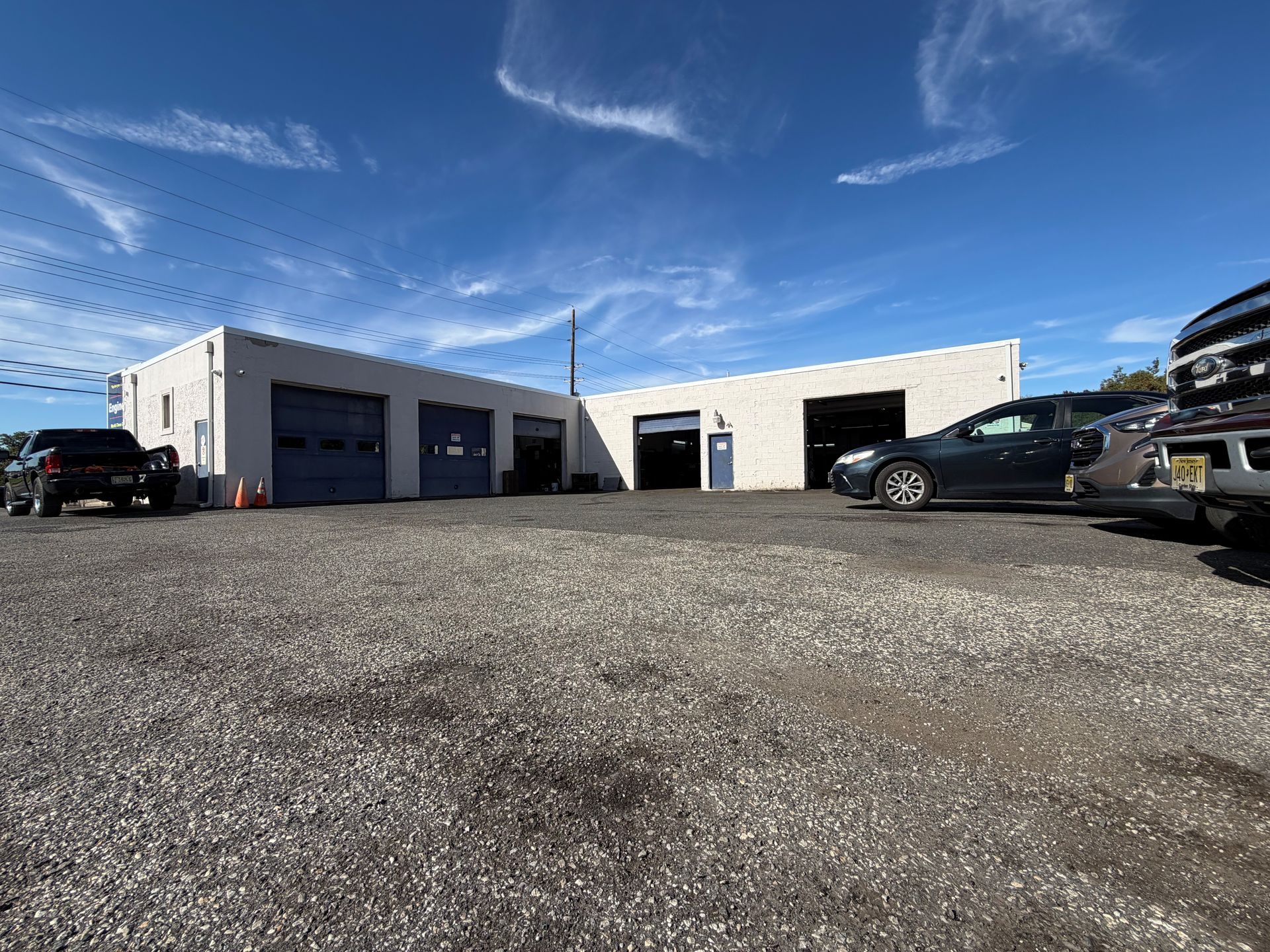Low-angle view of a white auto repair building with parked cars under a blue sky