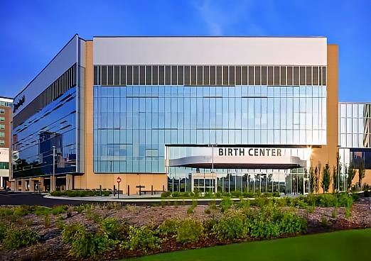 Modern glass birth center building with landscaped foreground and blue sky