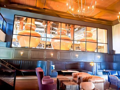Stylish restaurant dining area with booths, tables, and large orange pots displayed behind a glass wall