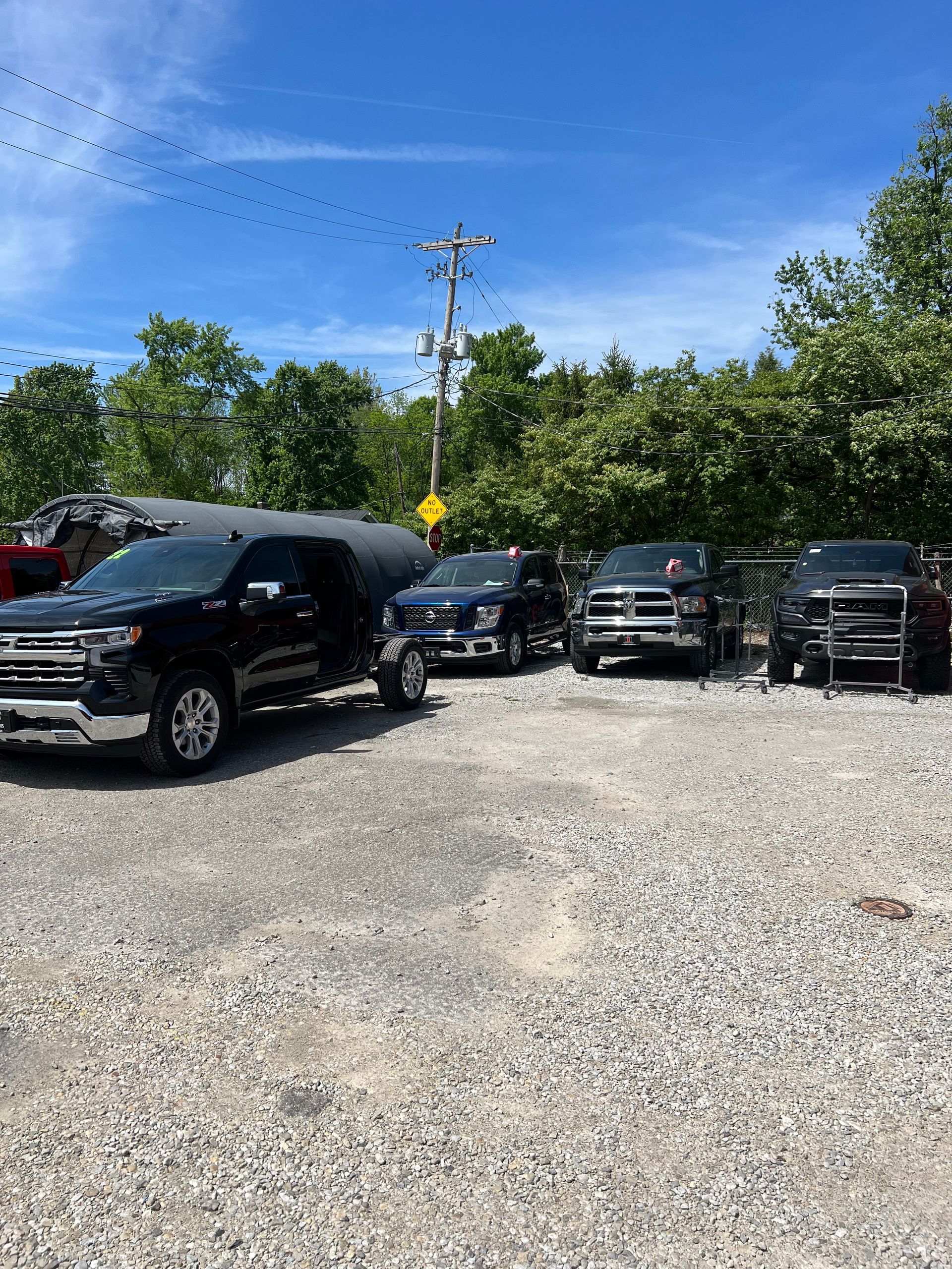 A row of trucks are parked in a gravel lot.