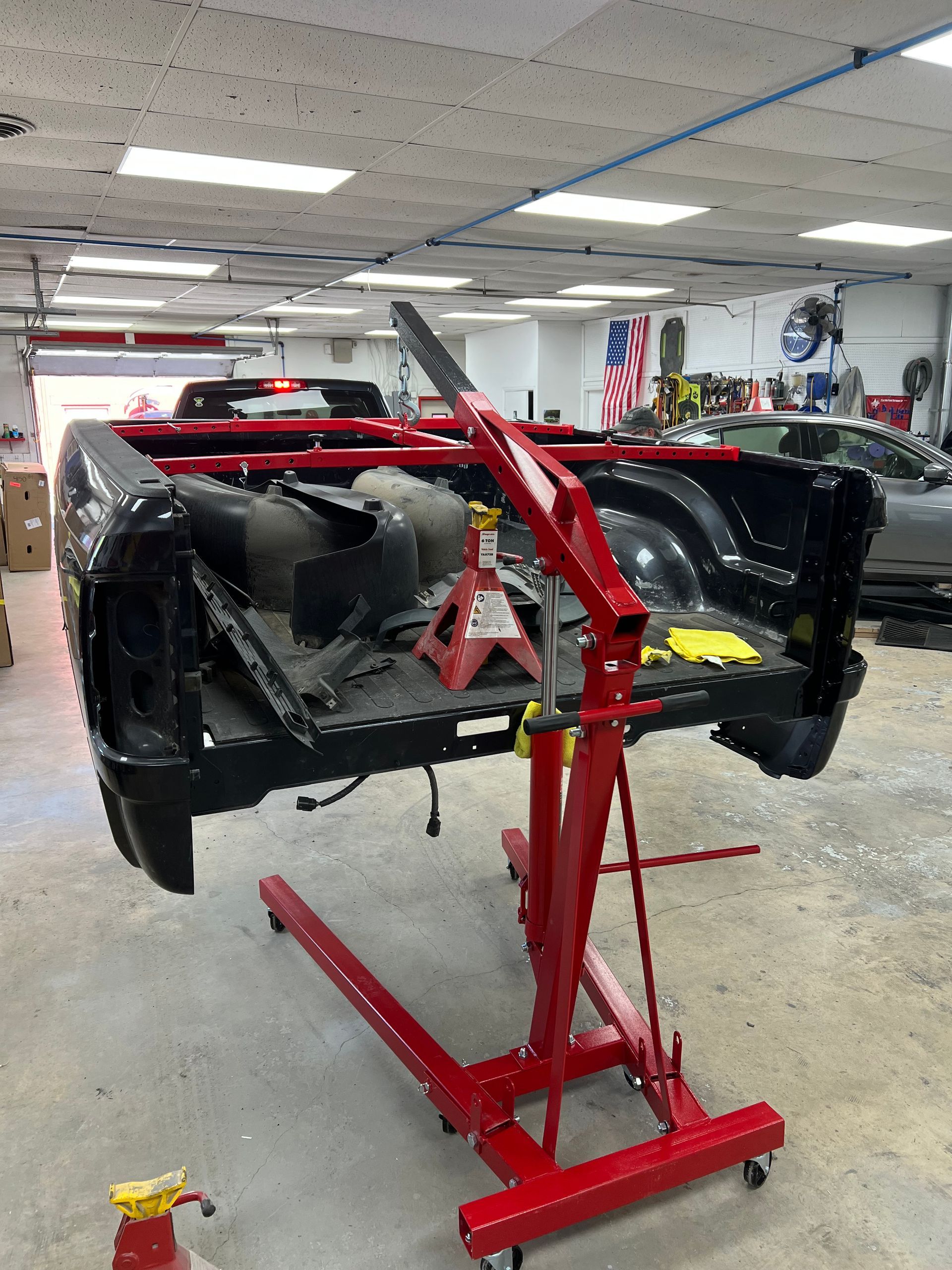 A truck is sitting on a red crane in a garage