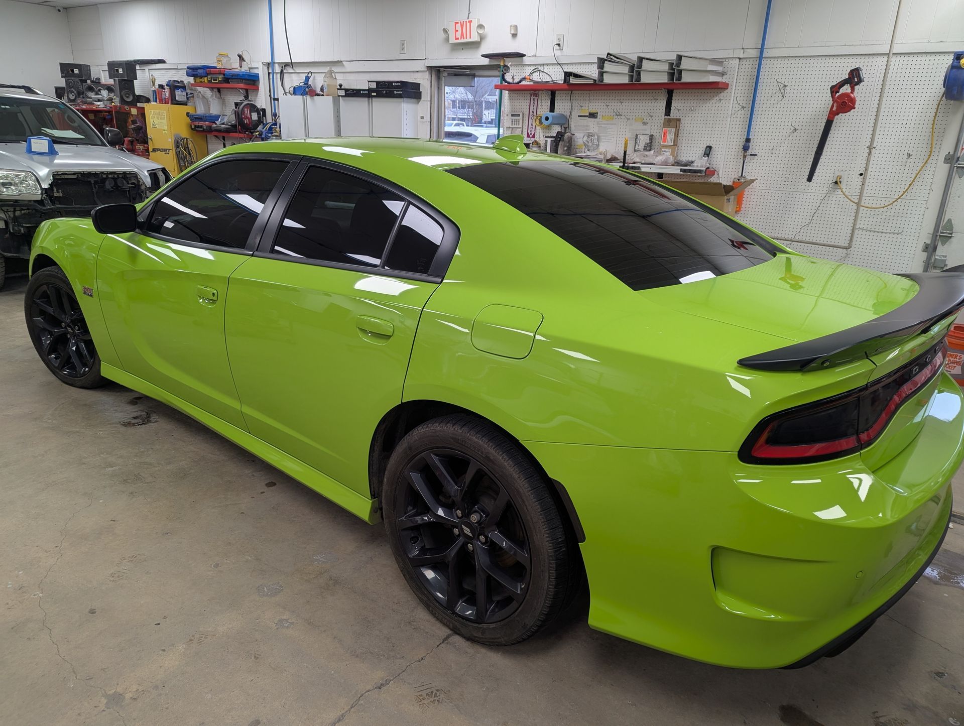 A green dodge charger is parked in a garage.