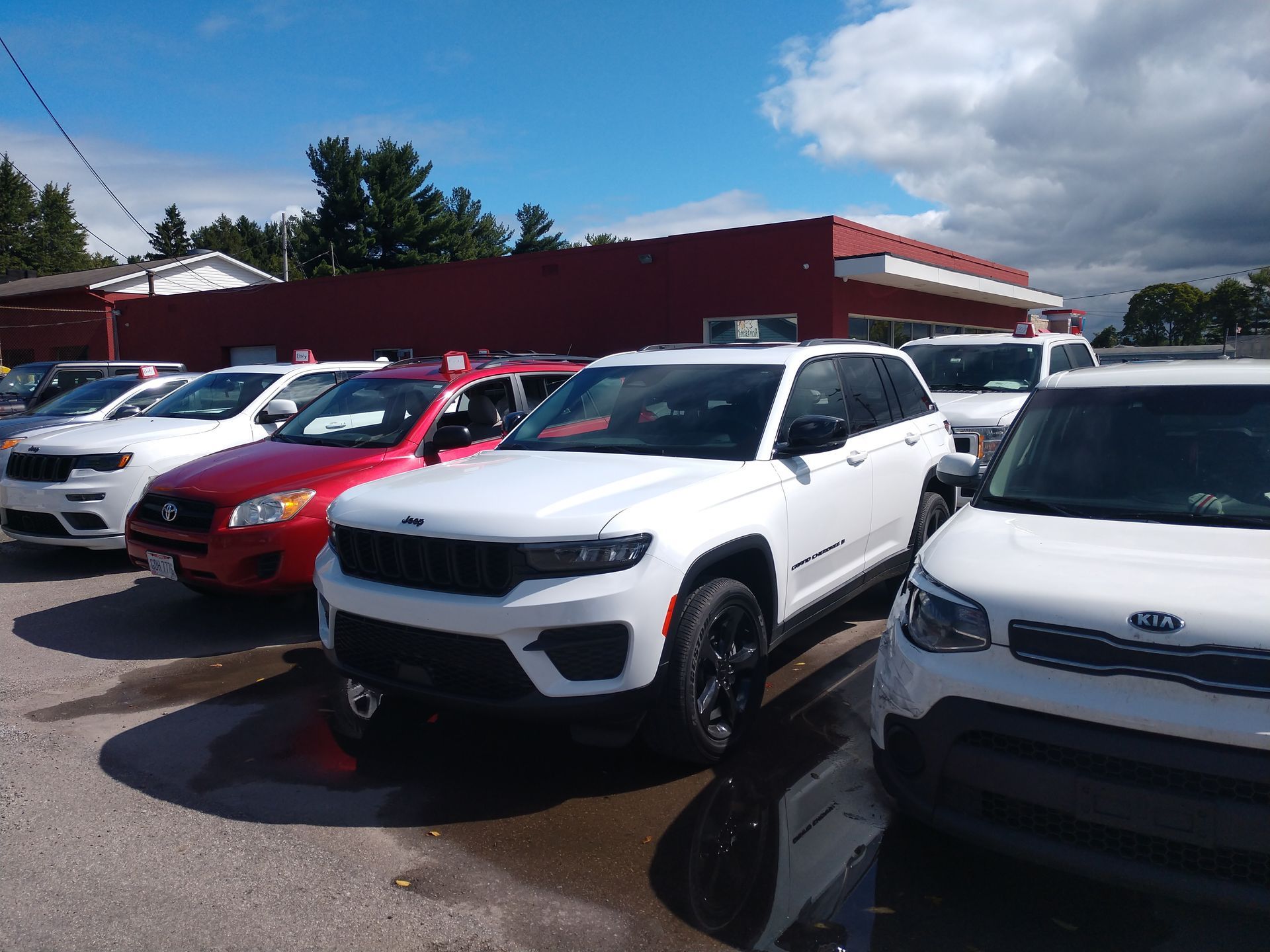 A row of cars are parked in front of a red building