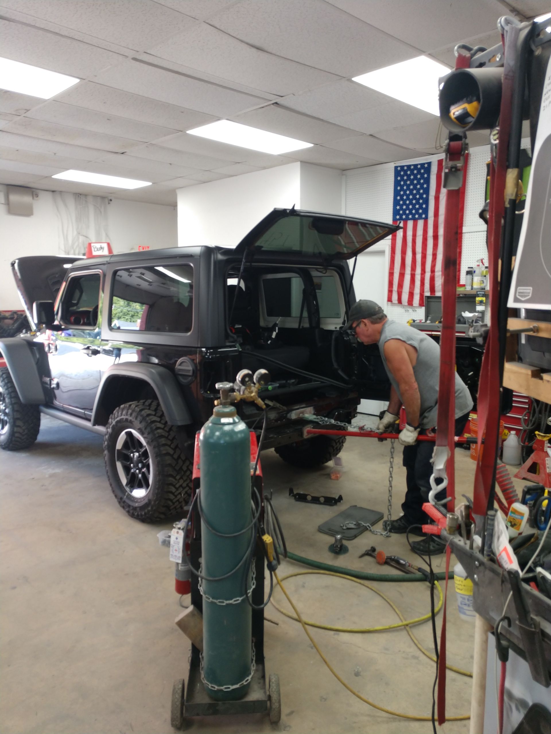 A man is working on a jeep in a garage.