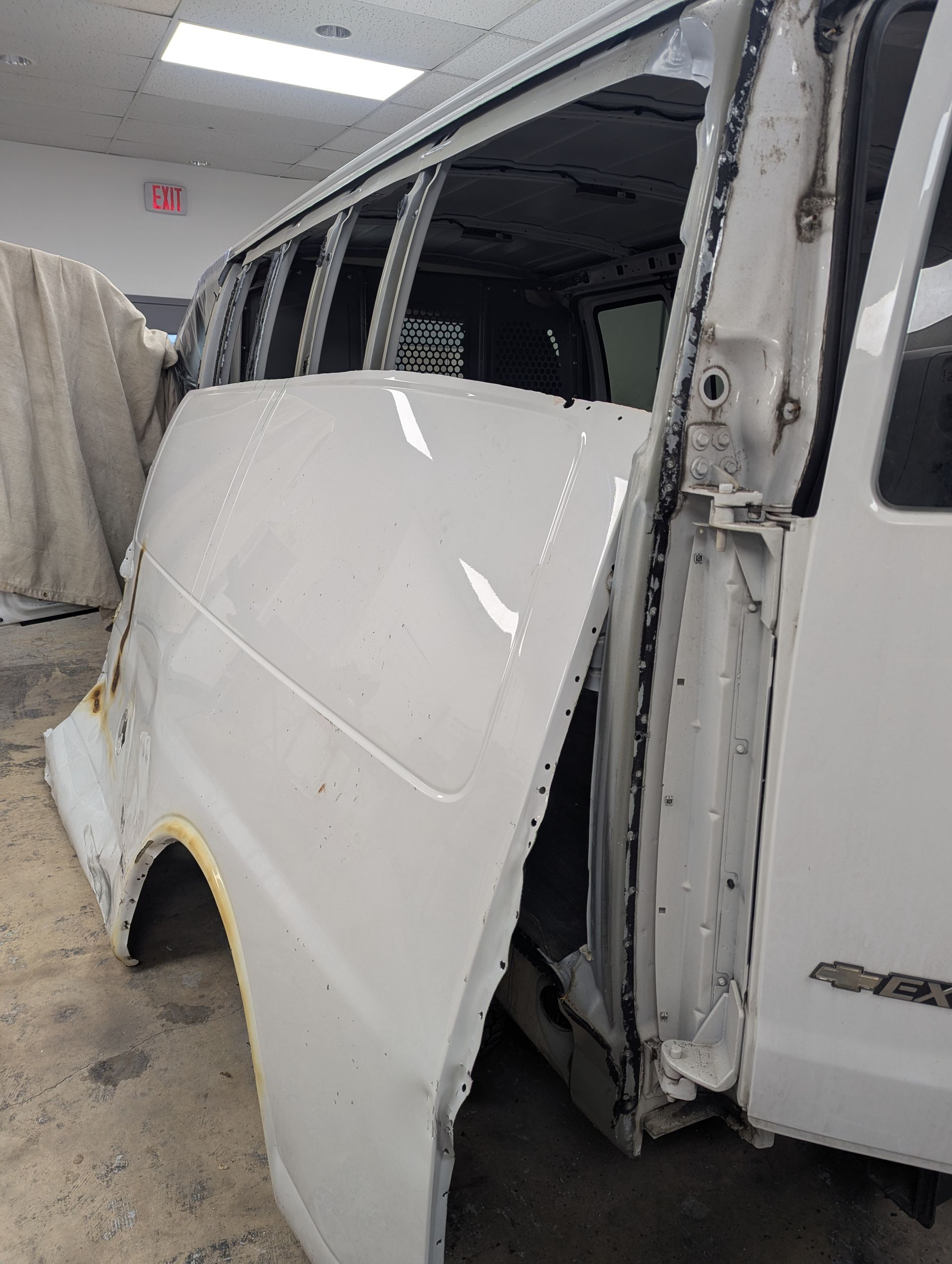 A white van is sitting in a garage with the door open.