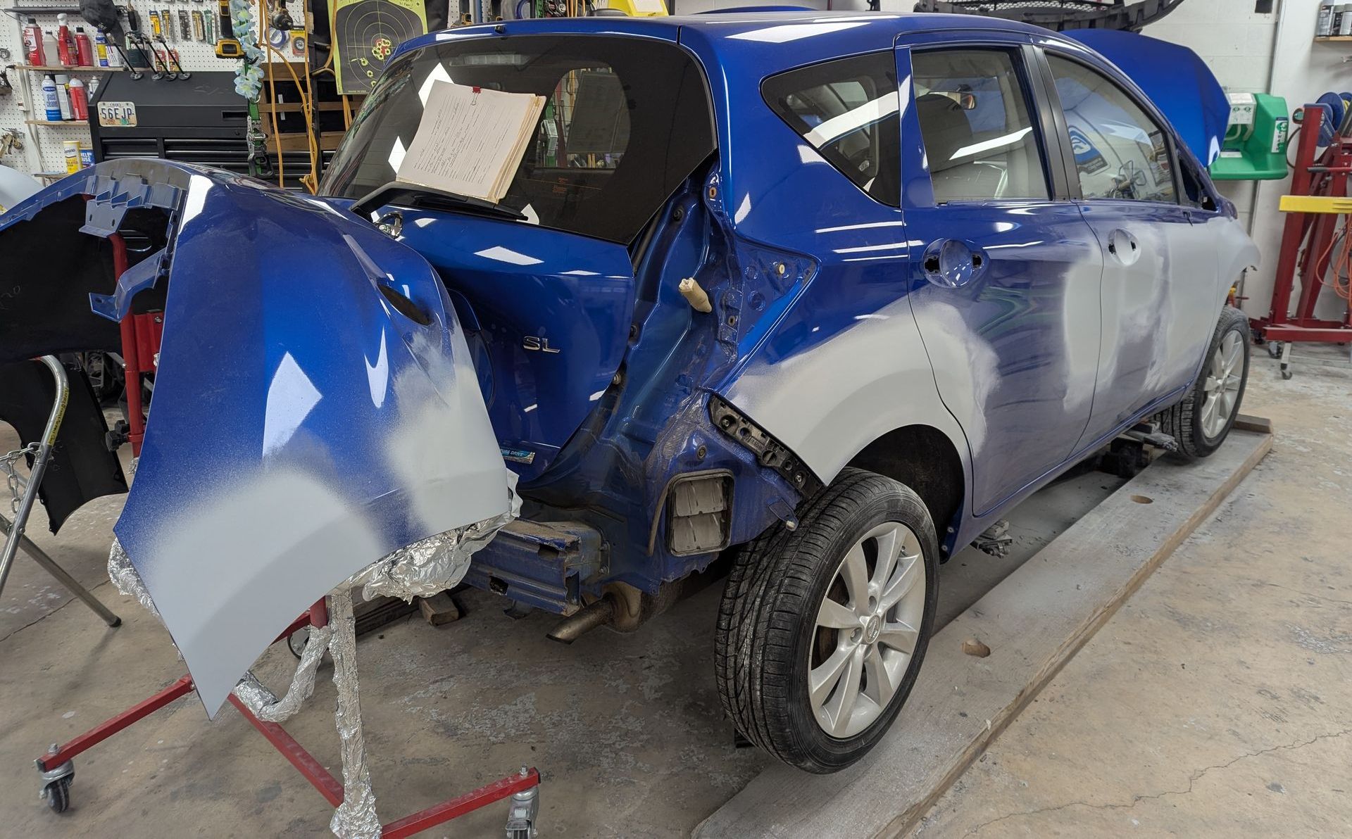 A blue car is being painted in a garage