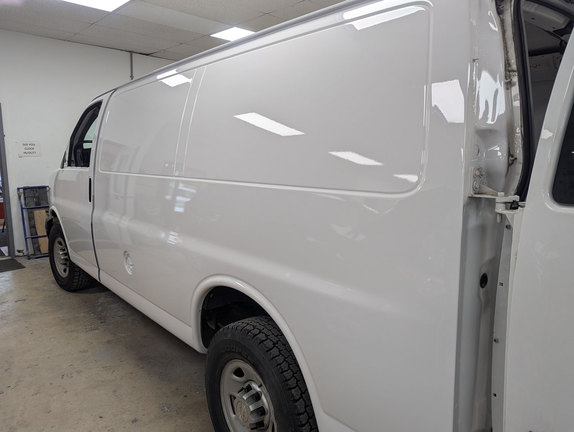 A white van is parked in a garage with its door open.